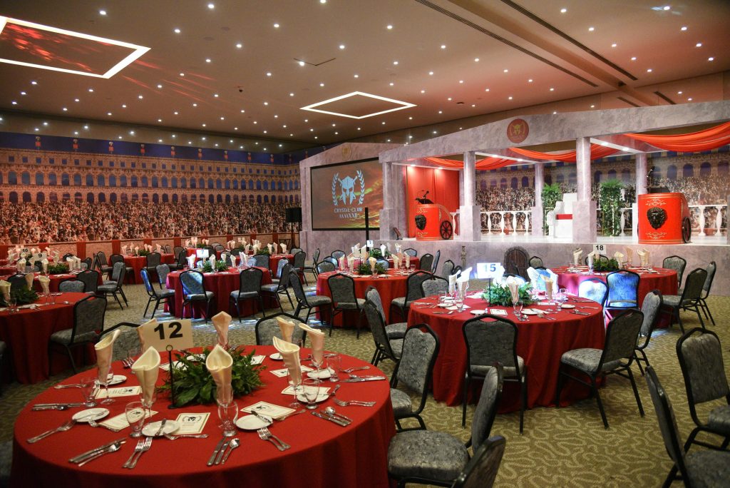 Luxurious setup for a Roman-themed event with red table settings, ideal for formal dinners or parties.