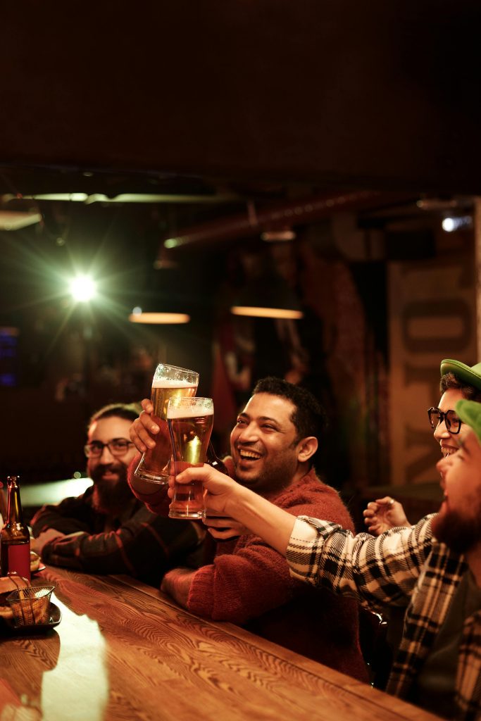 Group of friends enjoying drinks and laughter indoors at a pub.